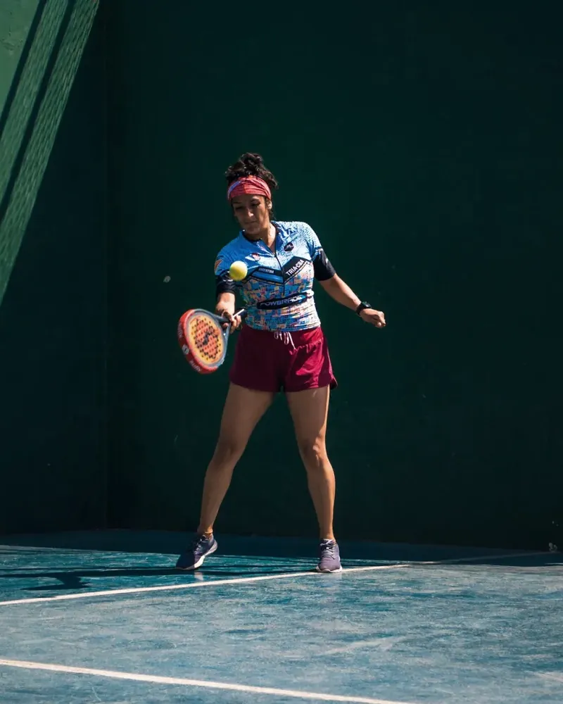 Padel player hitting a forehand near the wall