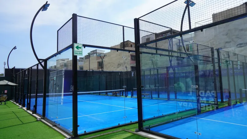 Outdoor padel court with glass walls and a blue surface