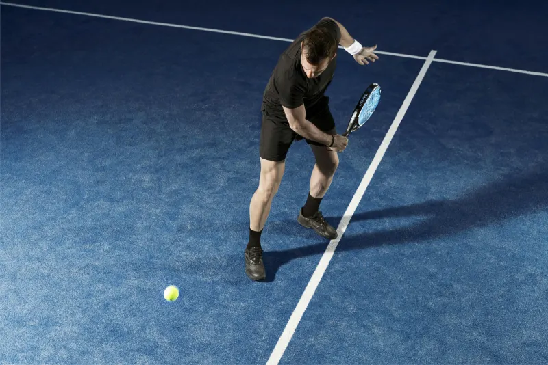 Padel player in black waiting for the ball on a blue court