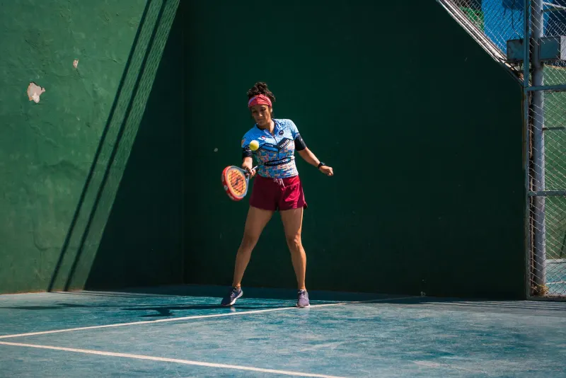 Padel player hitting a forehand in front of the green wall