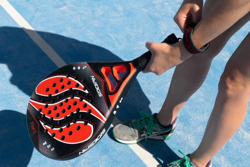 Player holding a padel racket on a blue court